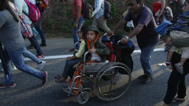 Un migrante, parte de una caravana que se dirige a la frontera entre México y Estados Unidos, empuja la silla de ruedas de un menor por la carretera en Escuintla, Chiapas, México. Imagen, AP.