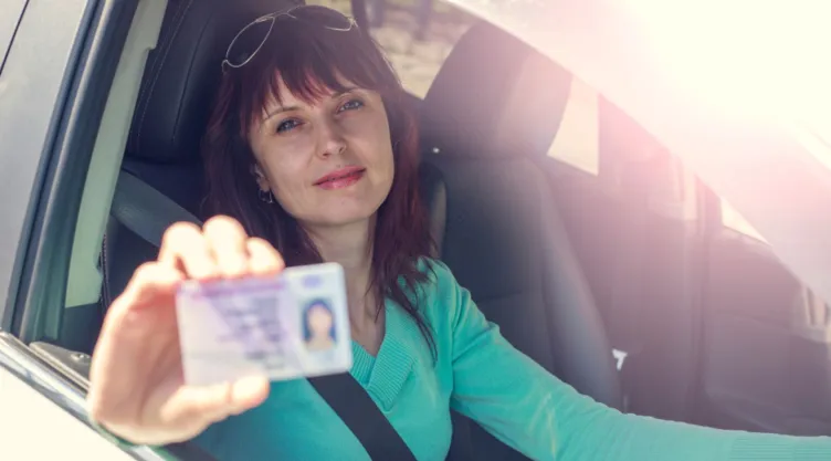 Una mujer muestra su licencia de conducir.