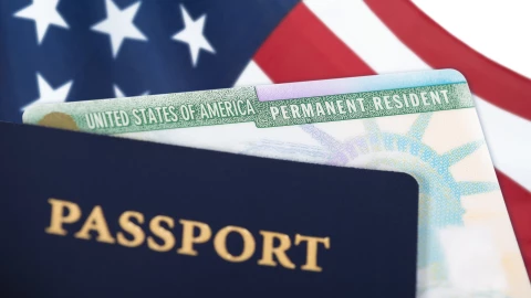 Un pasaporte, una Green Card y una bandera estadounidense.