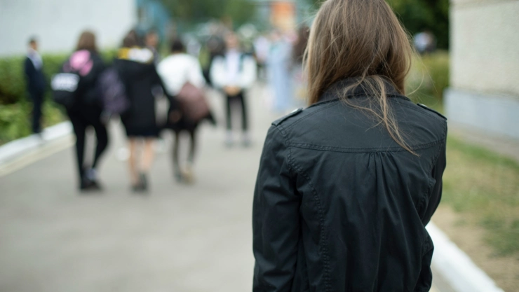 Una adolescente con campera negra ingresando a la escuela
