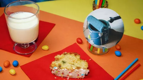 Pastel y leche sobre mesa con hojas de papel e imagen de bote de pintura azul.