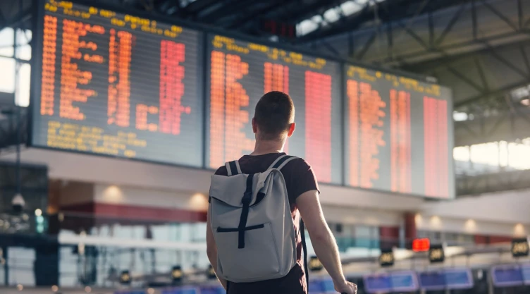 Postal de un hombre con mochila y maleta en un aeropuerto.