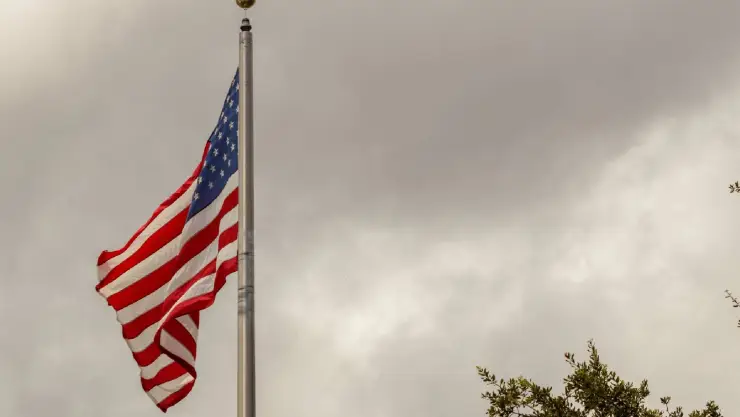 la bandera estadounidense con un fondo de nubes grises y espesas