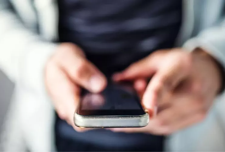hombre sosteniendo un tel&eacute;fono en sus manos