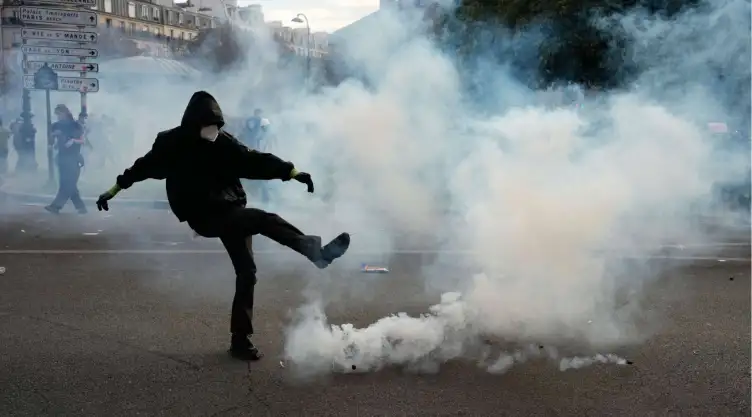 Un manifestante patea una lata de gas lacrimógeno en París.