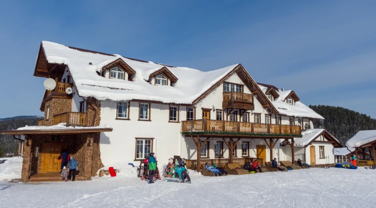 Un centro de esquí, con el edificio principal cubierto de nieve y los visitantes en el lugar