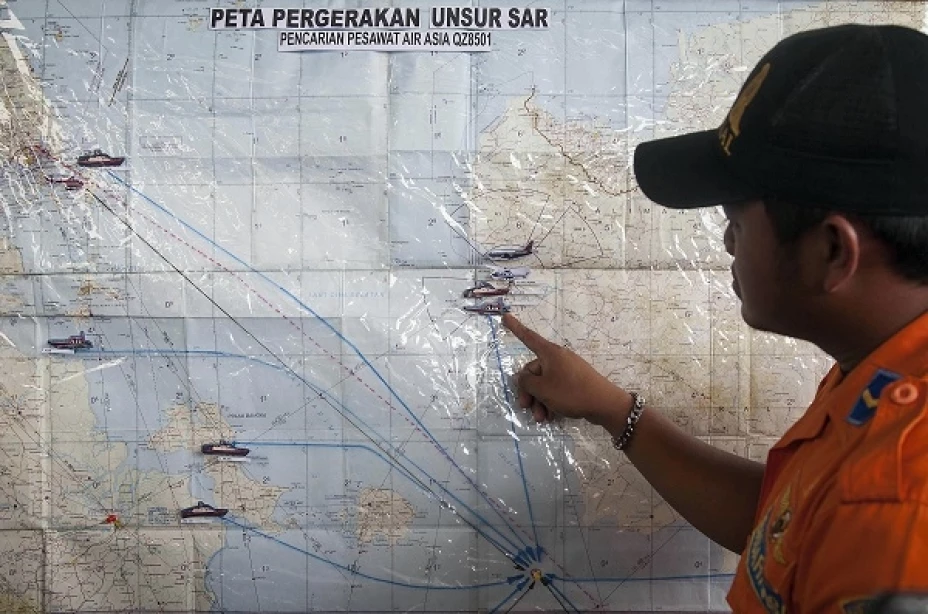 Un agente de búsqueda y rescate señala un mapa de coordinación en el centro de crisis formado por las autoridades locales para buscar un avión desaparecido de Air Asia