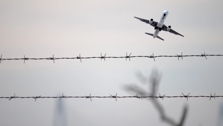 Un avión sobrevuela una valla de alambre.