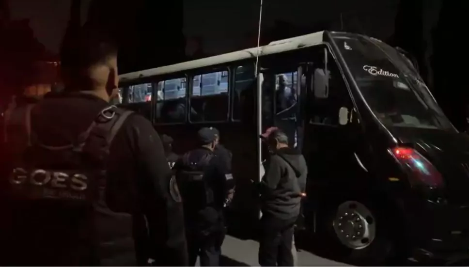 personal de seguridad resguardando un autobús en el que se transporta a migrantes