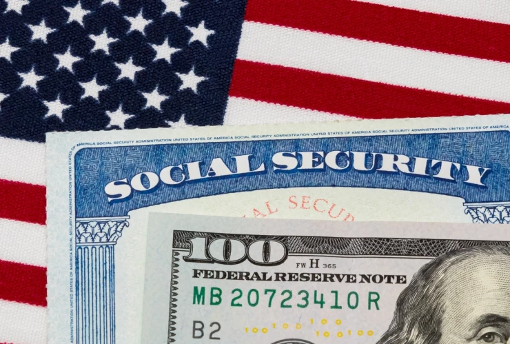 Cheque del Seguro Social junto a dólares y la bandera de EU