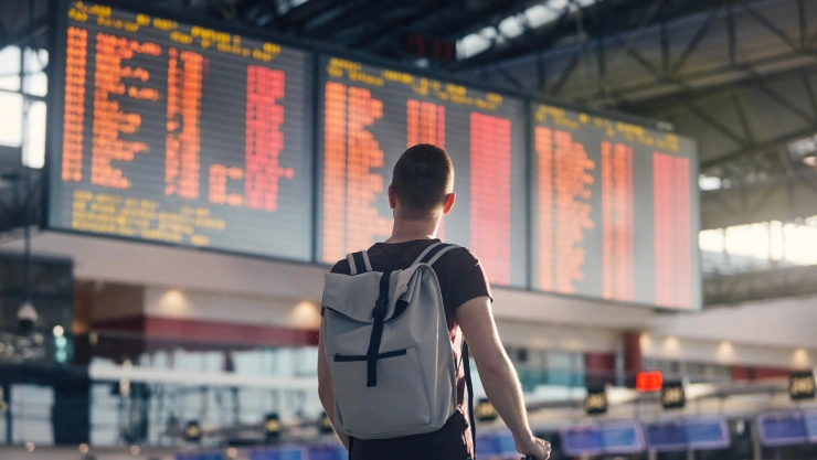 Postal de un hombre con mochila y maleta en un aeropuerto.