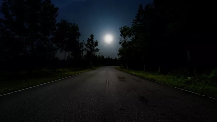 Una carretera de noche que se ilumina sólo con la luz de la luna llena.