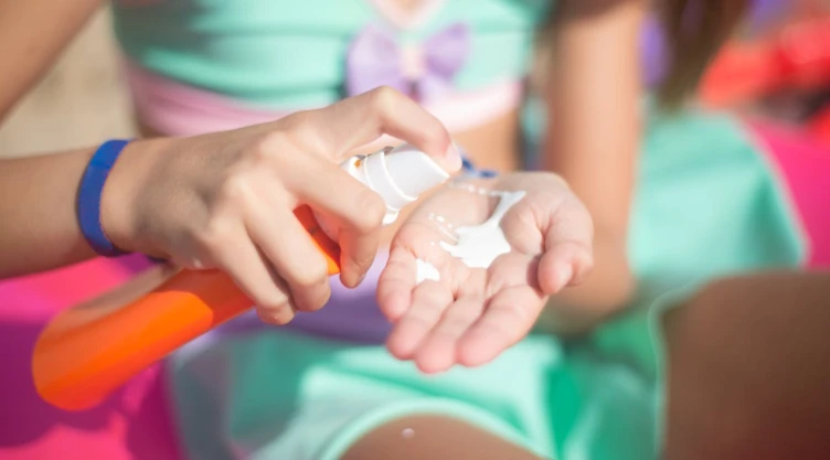 Una pequeña niña se aplica bloqueador solar antes de meterse al agua.