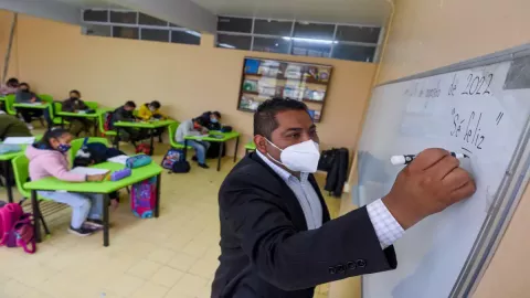 Maestro dando clases a sus alumnos en un salón escolar