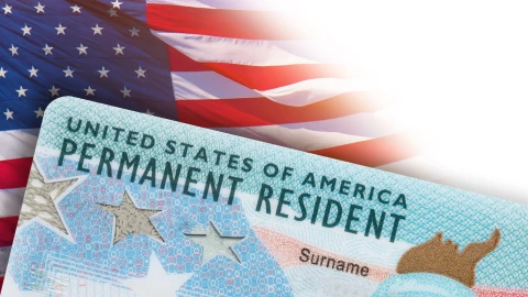 Una Green Card sobre una bandera estadounidense