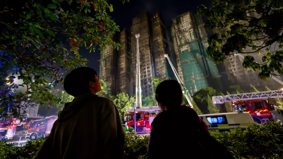 Foto de la gente se encuentra cerca de la escena de un incendio mortal, que estalló ayer en el complejo de viviendas Wang Fuk Court, mientras los bomberos continúan los esfuerzos para extinguirlo, en Hong Kong , China, el 27 de noviembre de 2025.