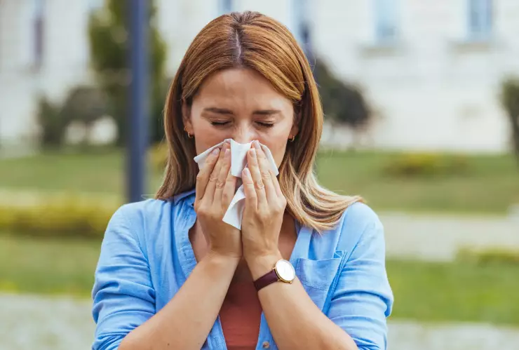 Una mujer se suena la nariz por alergia.