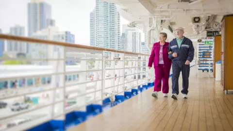 Dos personas de la tercera edad caminan por un crucero.