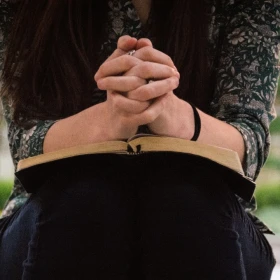 Mujer orando sobre biblia.