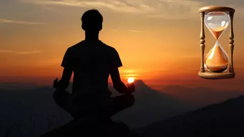 Persona meditando. Una puesta de sol de fondo y un reloj de arena