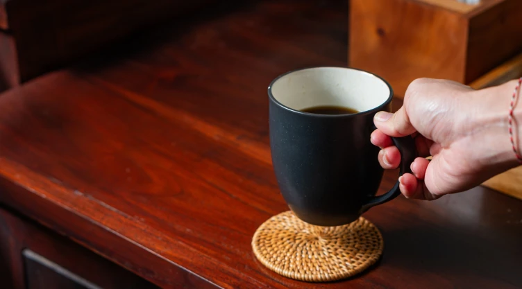 Una persona apoya una taza de café en la mesa.