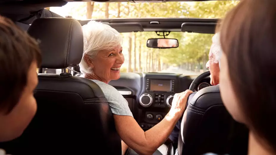 unos abuelitos manejan y llevan a pasear a sus nietos