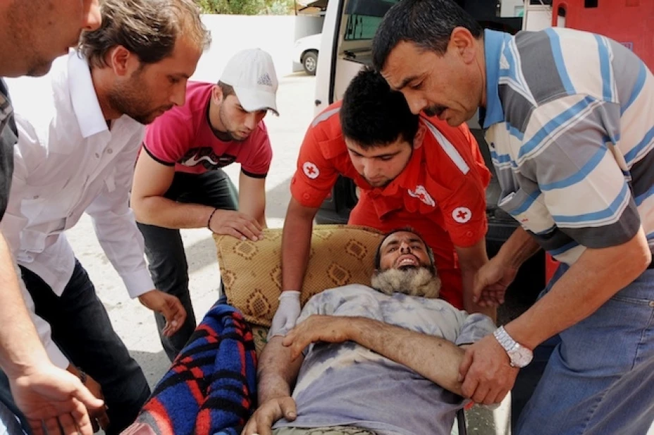 Socorristas de la Cruz Roja libanesa transportando a un hombre sirio herido