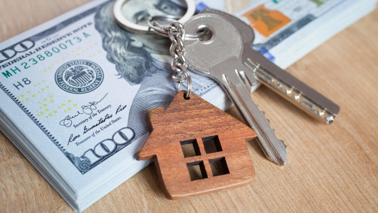 una imagen de dólares y la llave de una casa