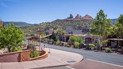 Una de las calles principales de un pueblo en Arizona, con sus casas bajas, las montañas de fondo y una escasa vegetación