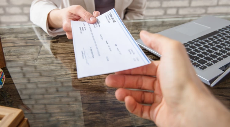 Una persona extiende un cheque de estímulo a otra