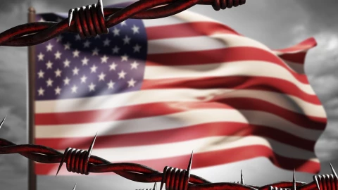 Bandera estadounidense tras un alambre de púas.