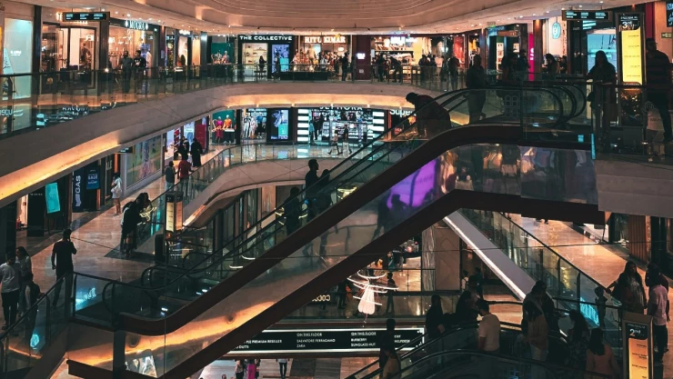 Foto de interior de centro comercial con tiendas y escaleras eléctricas.