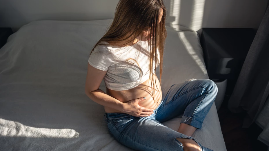 Pregnant woman on the bed in the room on a sunny morning.
