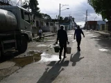 Un hombre transporta dos baldes de agua debido a la grave escasez de combustible que ha interrumpido el bombeo y la distribución de agua, en La Habana, Cuba, el 19 de marzo de 2026.