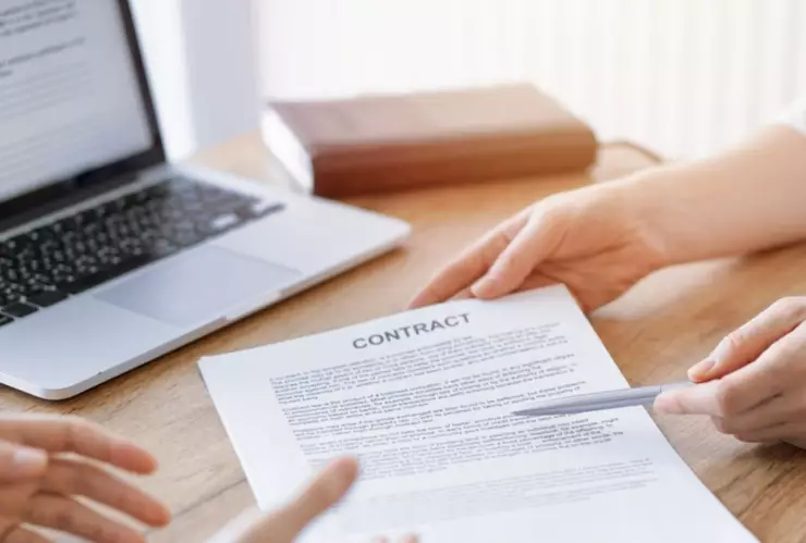 Una persona enseña un contrato de trabajo a otra.