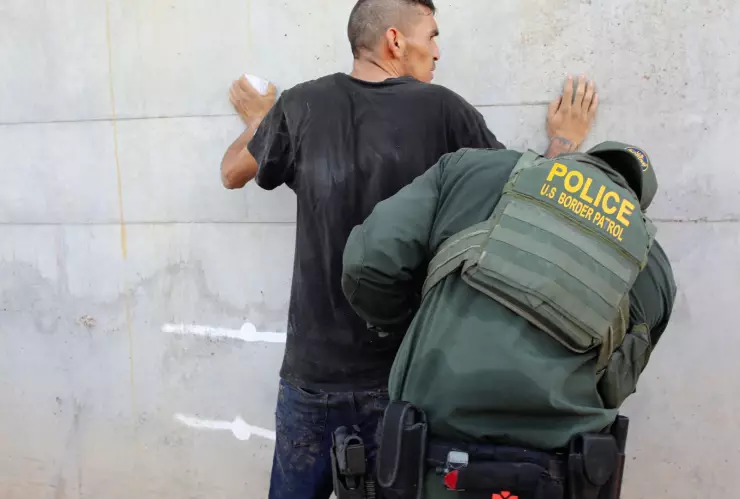 Una agente de ICE detiene a un extranjero