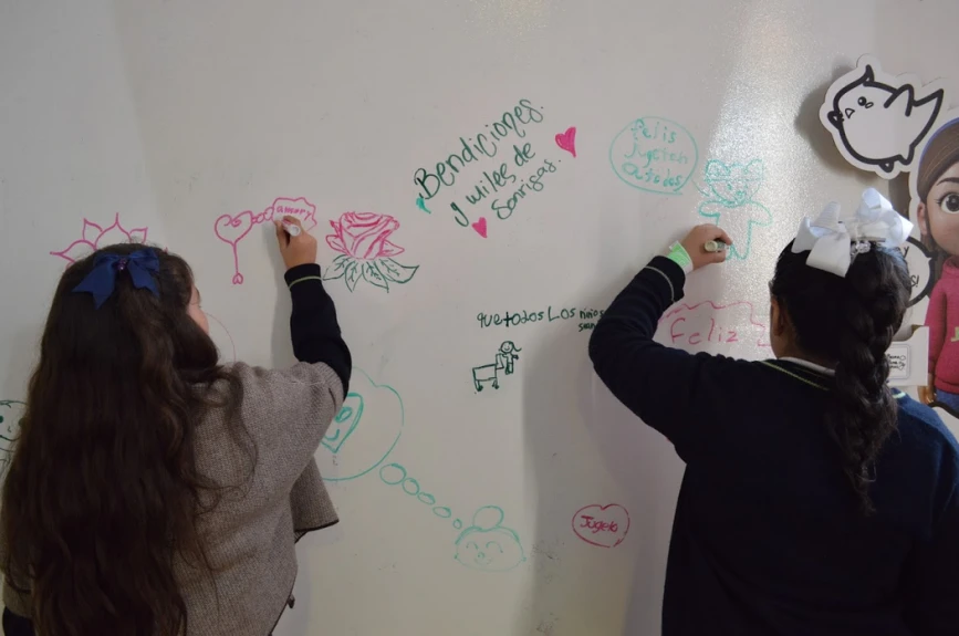 Alumnos de Jules Verné School dejando sus mensajes en el muro de la Villa Juguetón 25