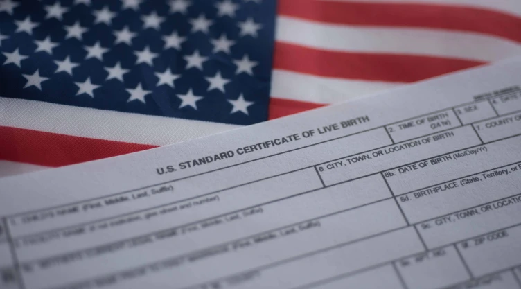 Certificado de nacimiento junto a la bandera de Estados Unidos