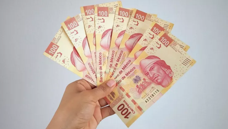 Billetes de 100 pesos mexicanos en la mano de una persona