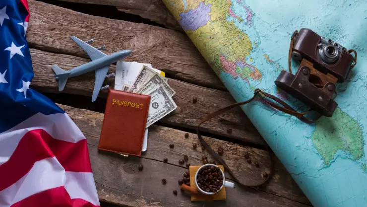 Una imagen de la bandera estadounidense junto a una cámara fotográfica antigua y un pasaporte