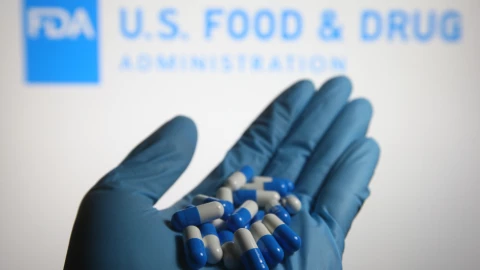 un m&eacute;dico con pastillas en su mano y la placa de la FDA