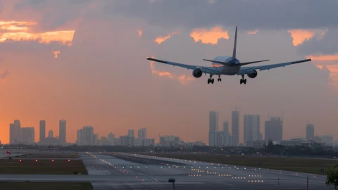 Un avión sobrevuela el Aeropuerto Internacional de Miami con un amanecer de fondo