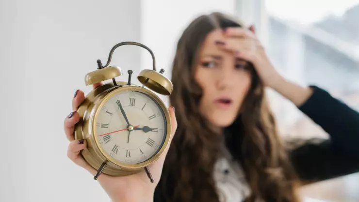 Una mujer sostiene un reloj y que indica la hora 