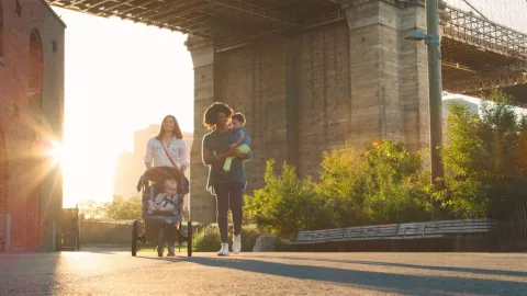 Una familia recorre un parque debajo al inicio del puente de Brooklyn.