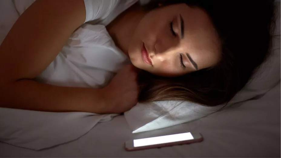 Mujer que duerme con celular en la almohada
