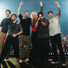 Músicos de la banda Linkin Park posando para tomarse foto con el publico de fondo después de un concierto desde el escenario