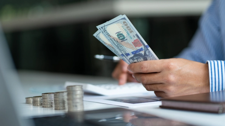 Una persona hace cálculos con dinero en dólares.