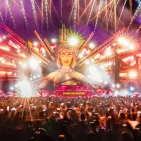 Escenario de festival musical con luces y escenografía con publico alzando las manos y disfrutando