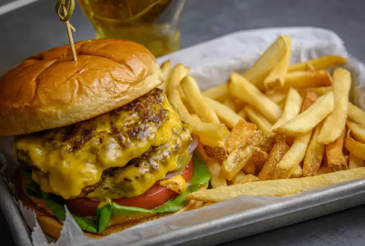 una deliciosa hamburguesa con doble carne y queso fundido acompañado de papas fritas