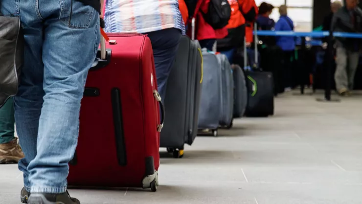 Unos viajeros hacen fila en un aeropuerto.